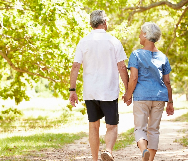 Photo of an older couple walking together down a leafy path